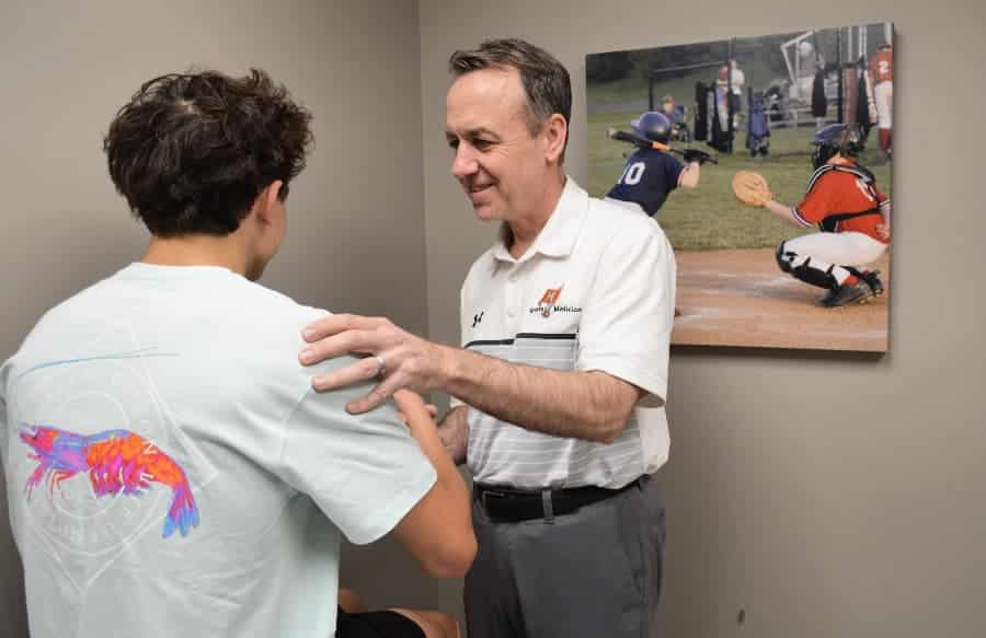 Dr. Michael Ellerbusch examining patients’ shoulder for an AC joint injury