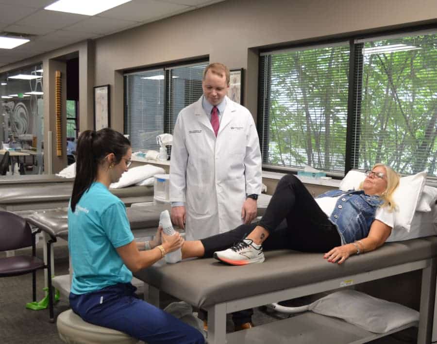 Dr. Lukasiewicz and a physical therapist treating woman for an achilles tendon injury