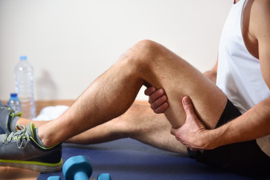 Athletic person sitting down and holding back of thigh