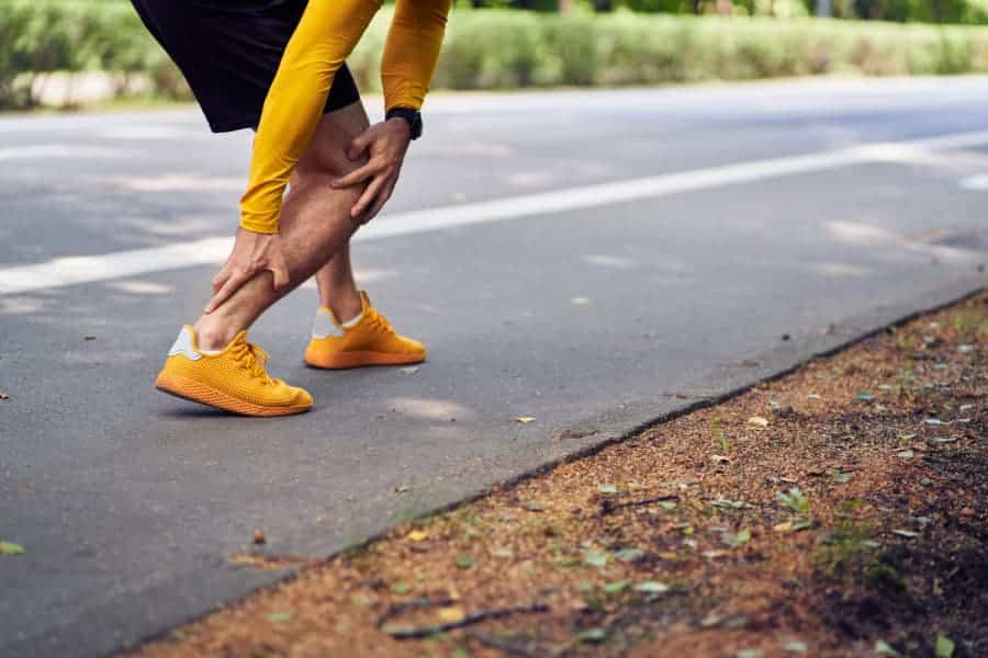 Runner holding hurt ankle with Achilles tendon injury