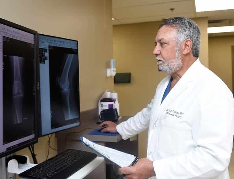 Dr. Michael F. Blum examining knee x-rays on computer screens