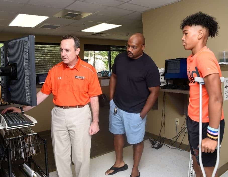 Dr. Michael T. Ellerbusch showing computer screen to young patient on crutches and parent
