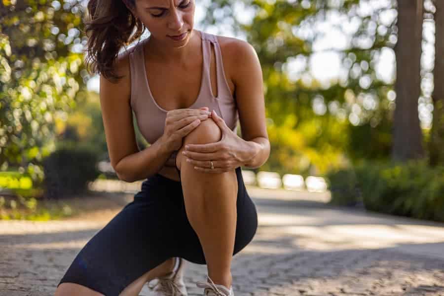 Young athletic person experiencing knee pain while running outside