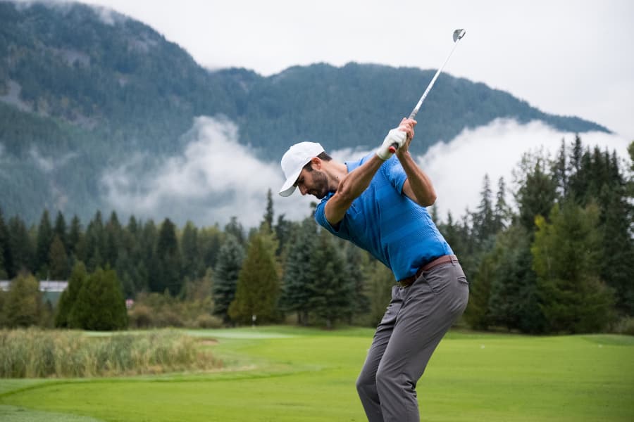Golfer with raised club preparing to make shot on scenic course