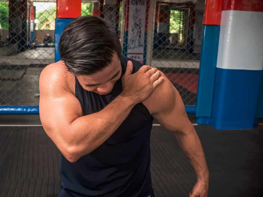 Bodybuilder grabbing back of shoulder while in gym