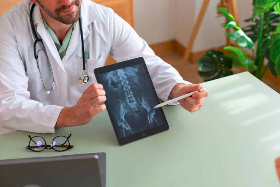 Doctor showing pelvic x-ray on tablet to patient in medical office