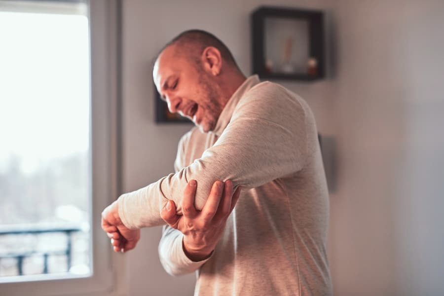 Person at home holding elbow in pain