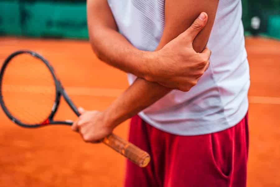 Close-up image of tennis player holding injured elbow