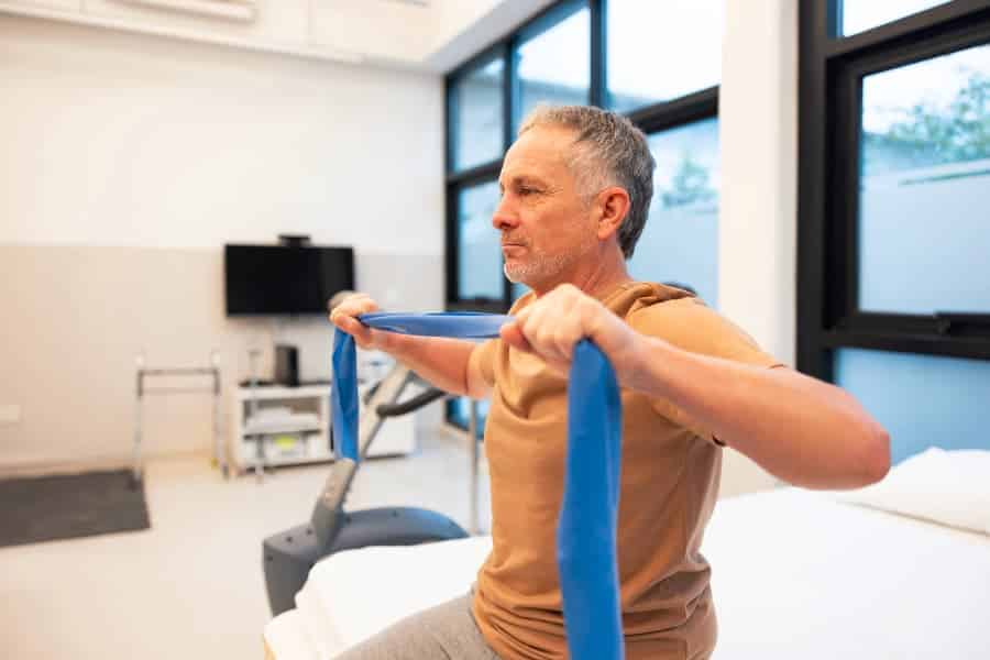 Patient in physical therapy doing shoulder exercises with resistance band